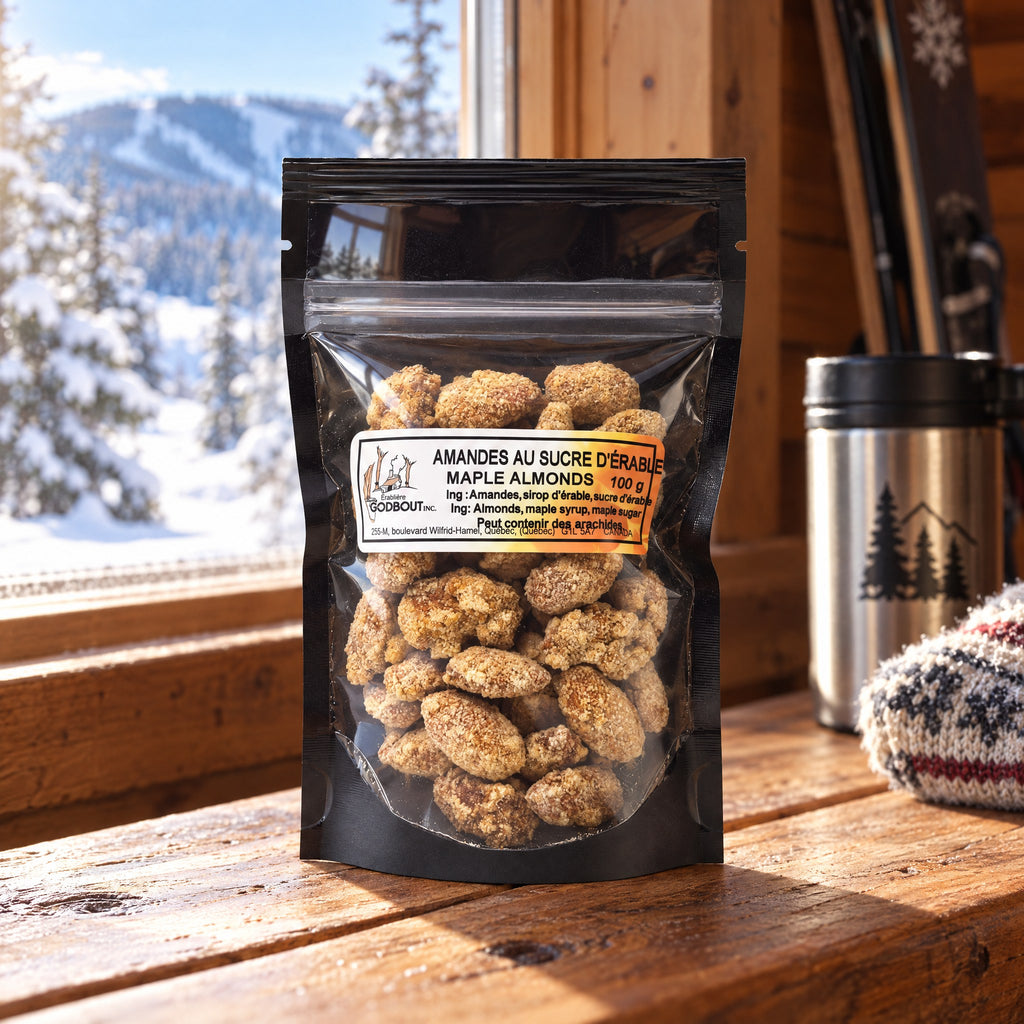 Sachet d'amandes au sucre d'érable posé sur un rebord de fenêtre en bois devant un paysage de montagne enneigé