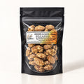Sachet noir transparent rempli d’amandes au sucre d'érable, posé debout sur un fond crème uniforme
