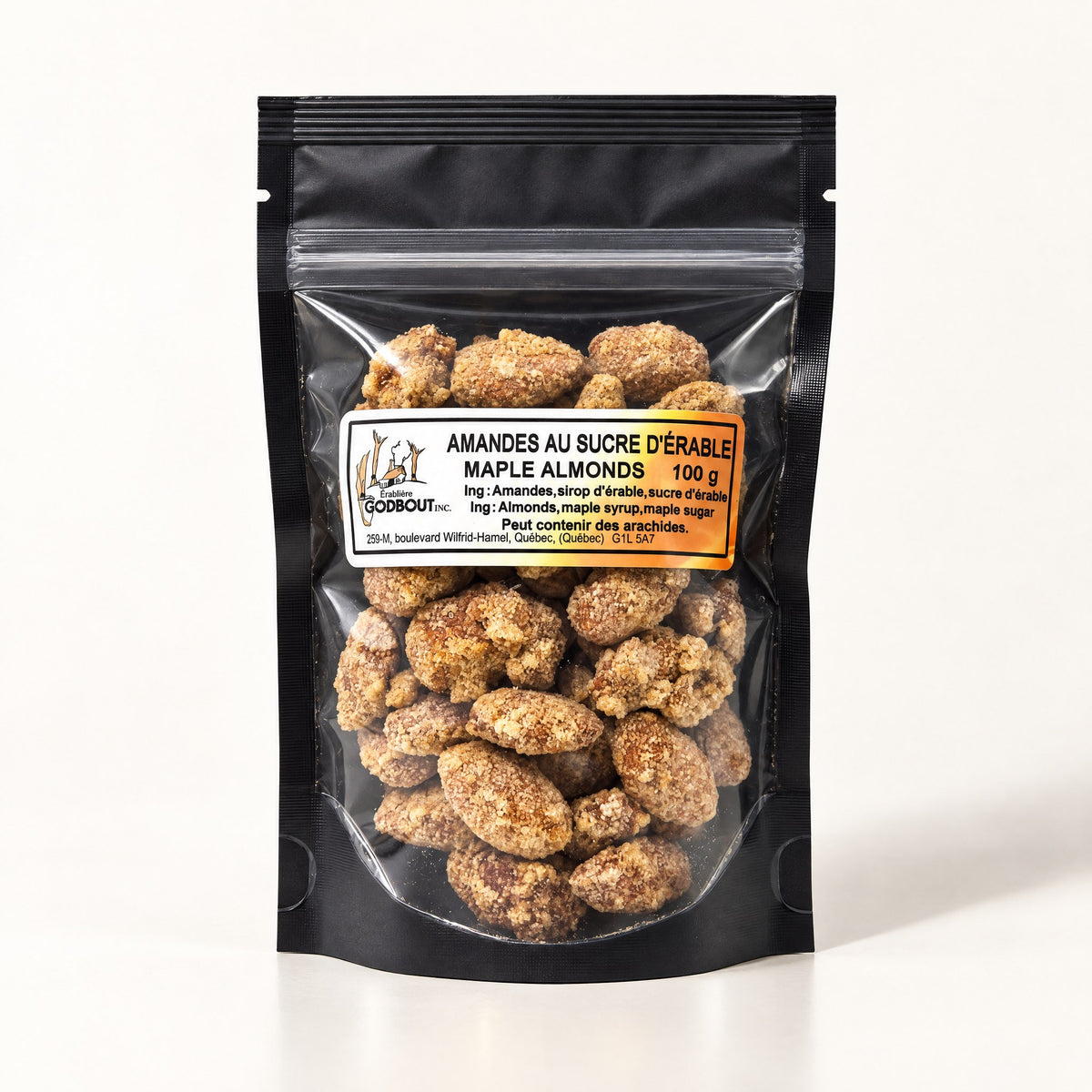 Sachet noir transparent rempli d’amandes au sucre d'érable, posé debout sur un fond crème uniforme