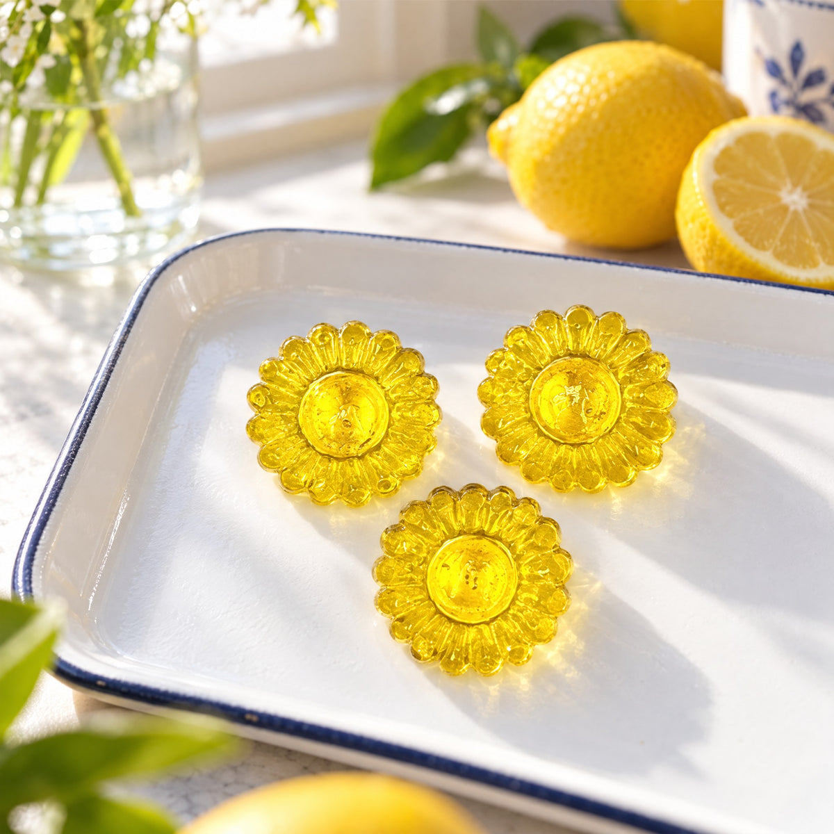Trois bonbons au miel et citron en forme de fleur sur un plateau blanc accompagnés de citrons frais