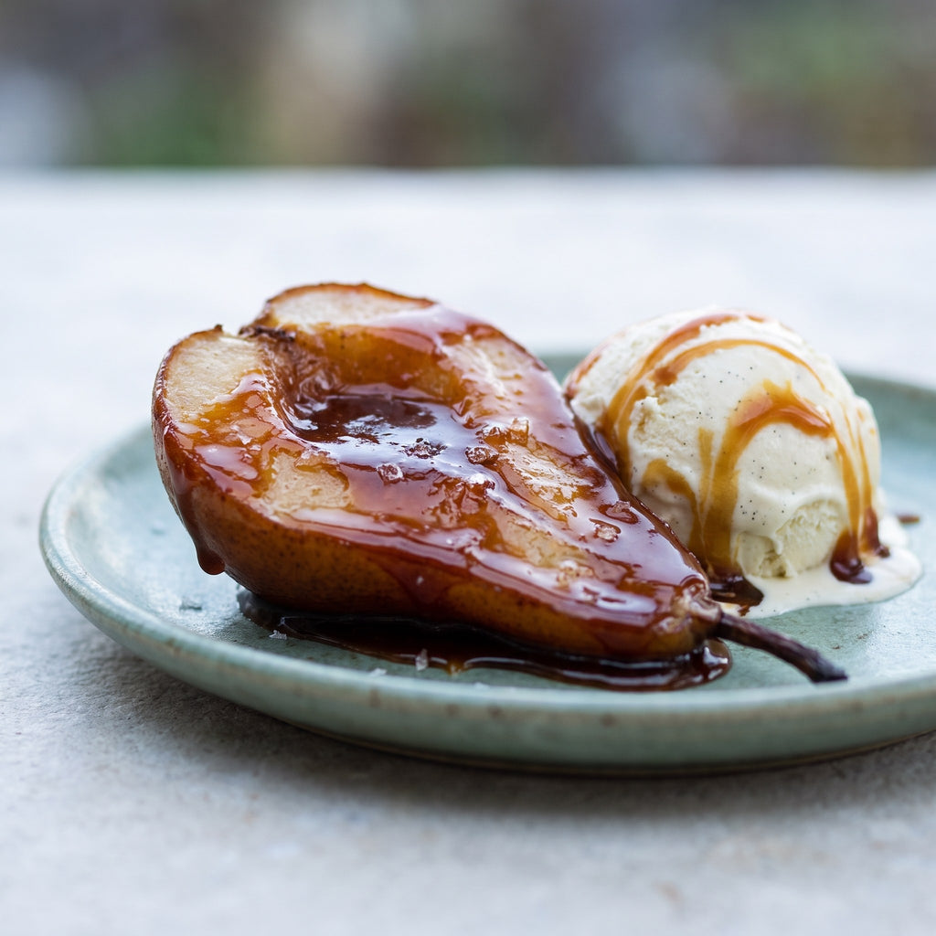 Demi-poire cuite nappée de caramel au miel et fleur de sel à côté d'une boule de crème glacée à la vanille