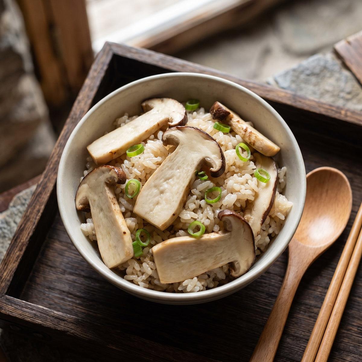 Bol de riz chaud garni de tranches de champignons matsutake et d'oignons verts ciselés sur un plateau en bois rustique