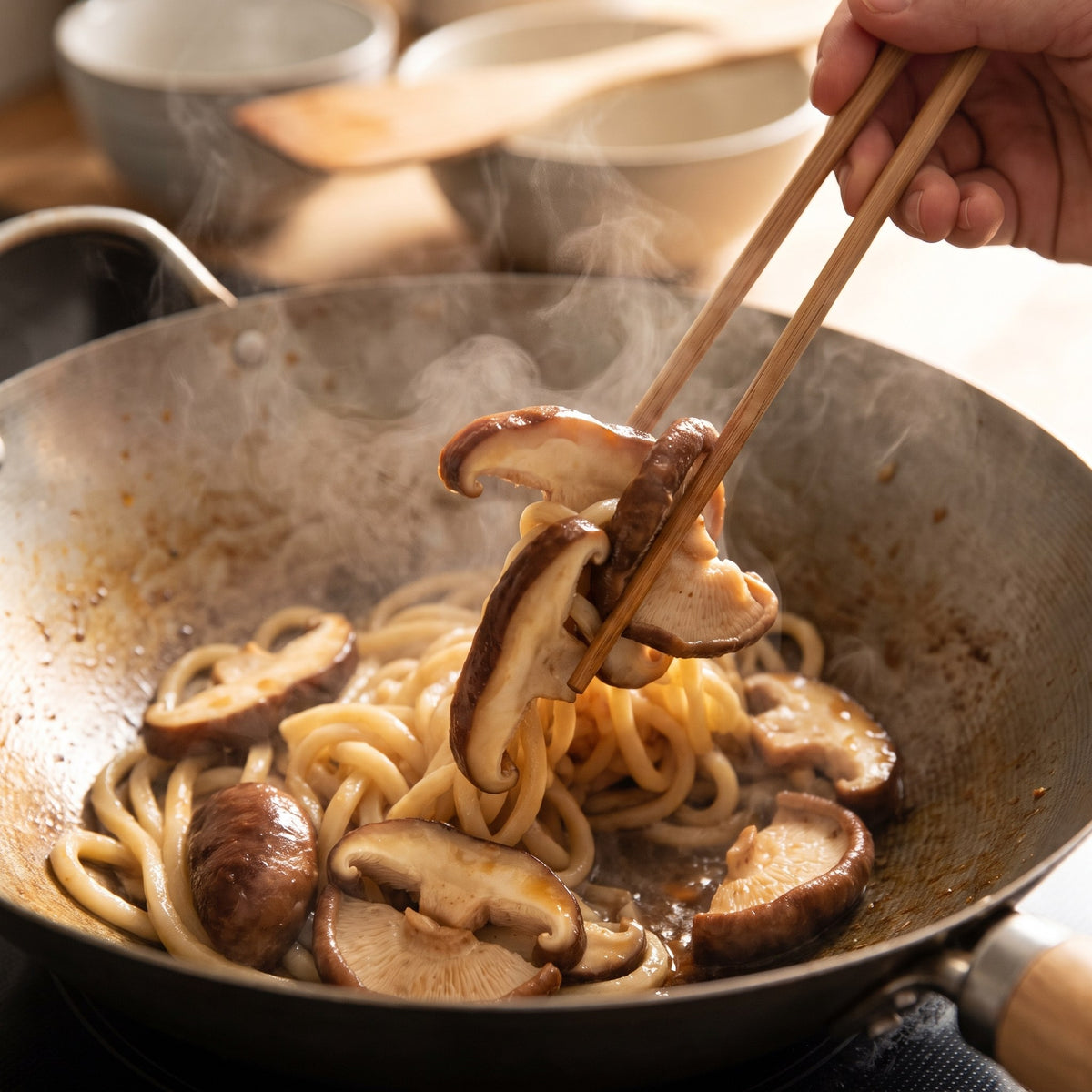 Des champignons shiitake sautés avec des nouilles fumantes dans un wok, saisis délicatement avec des baguettes en bois
