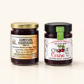 Deux pots de verre du duo de confitures — bleuets & cerises avec couvercles doré et noir sur fond crème