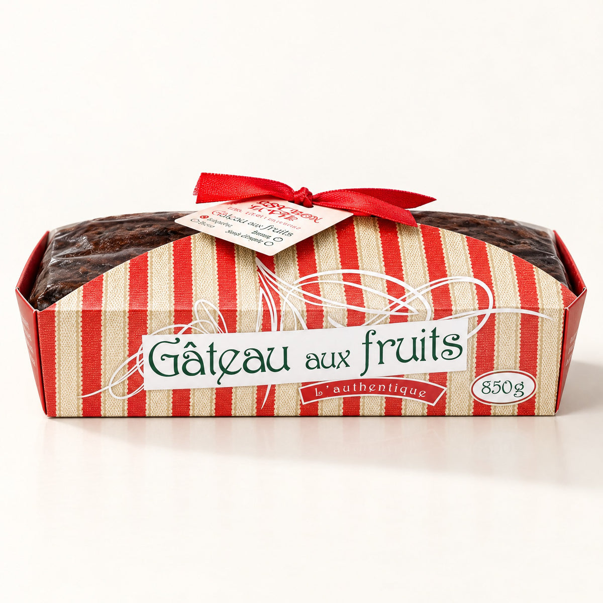 Un gâteau aux fruits traditionnel de 850 g présenté dans son moule rayé rouge et beige, sur un fond crème