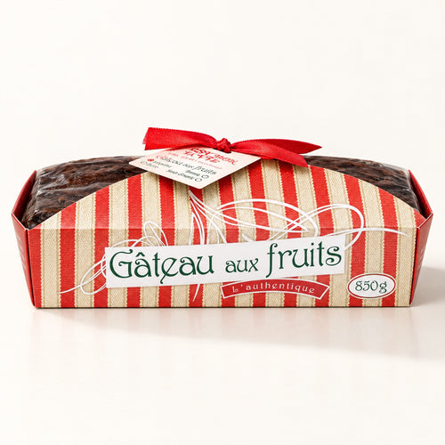 Un gâteau aux fruits traditionnel de 850 g présenté dans son moule rayé rouge et beige, sur un fond crème