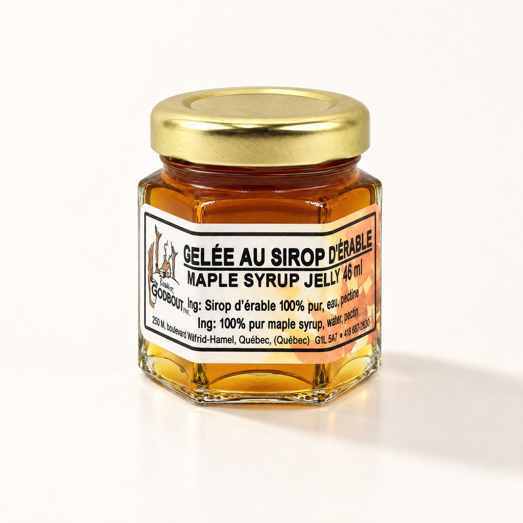 Un petit pot hexagonal de gelée au sirop d'érable fermé par un couvercle doré, posé sur un fond crème lumineux