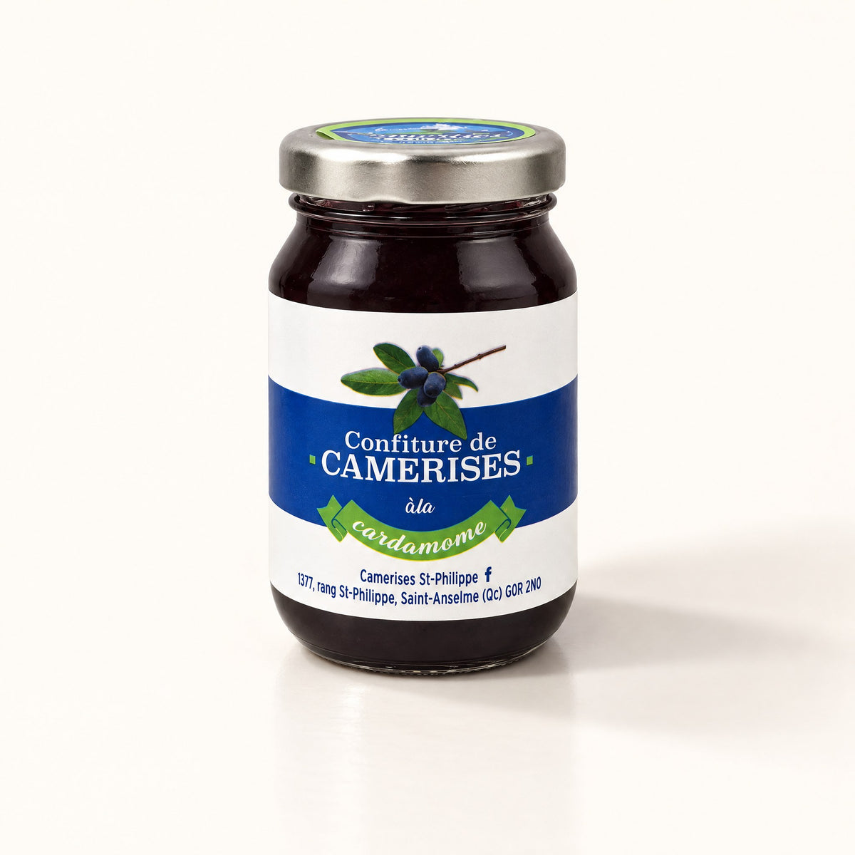 Un pot de gelée de camerises à la cardamome posé sur un fond crème épuré avec une ombre douce