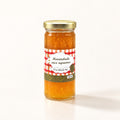 Un pot de marmelade aux agrumes sur fond crème avec son couvercle doré et son étiquette quadrillée rouge