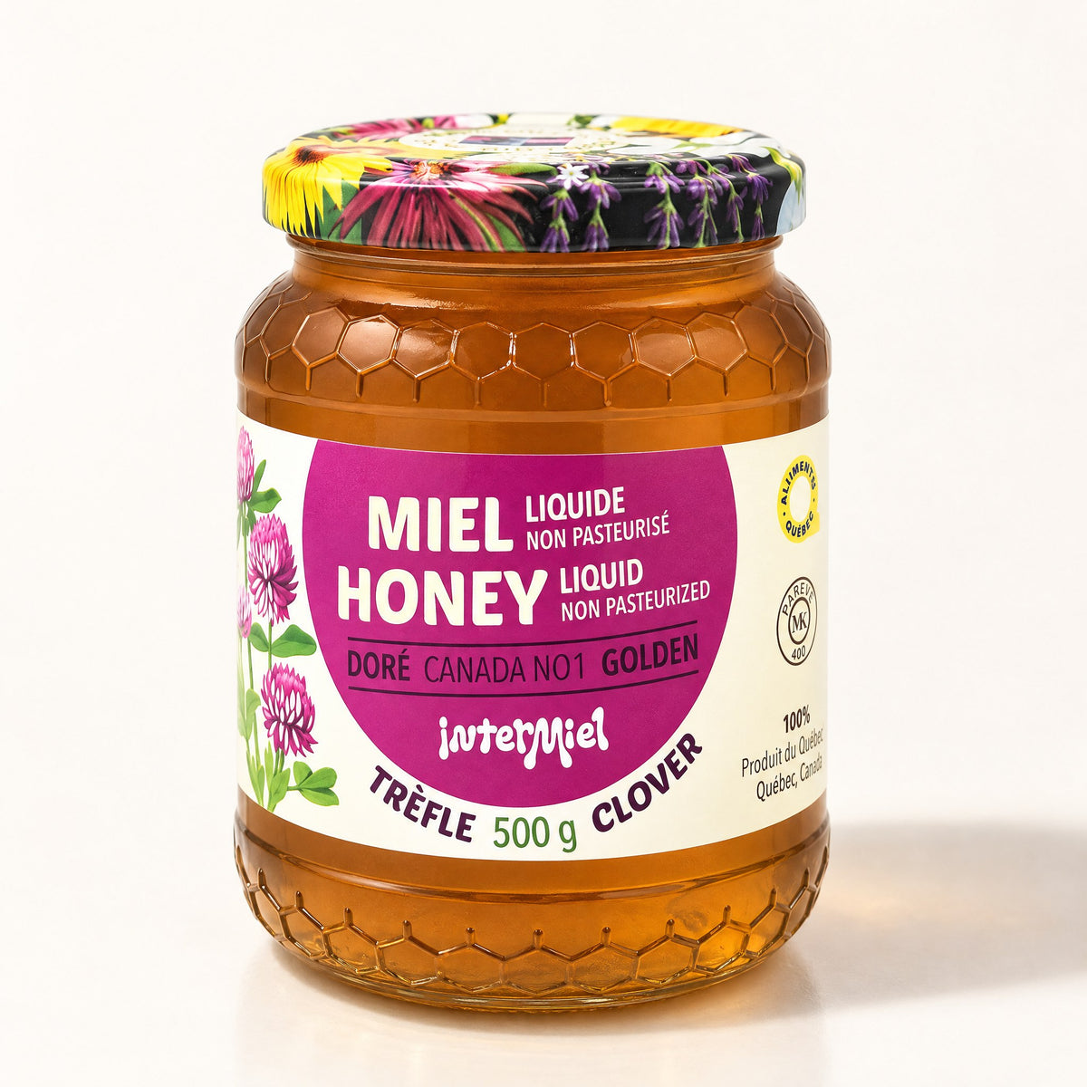 Pot de miel de trèfle Intermiel au verre texturé d’alvéoles et couvercle fleuri sur fond crème