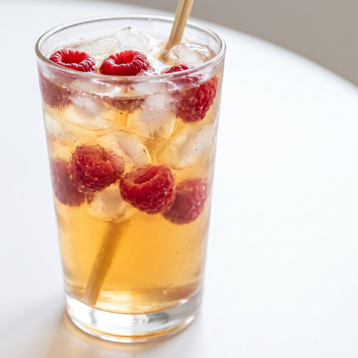 Verre de boisson au Miel framboisier glacée avec framboises fraîches et glaçons sur une table claire