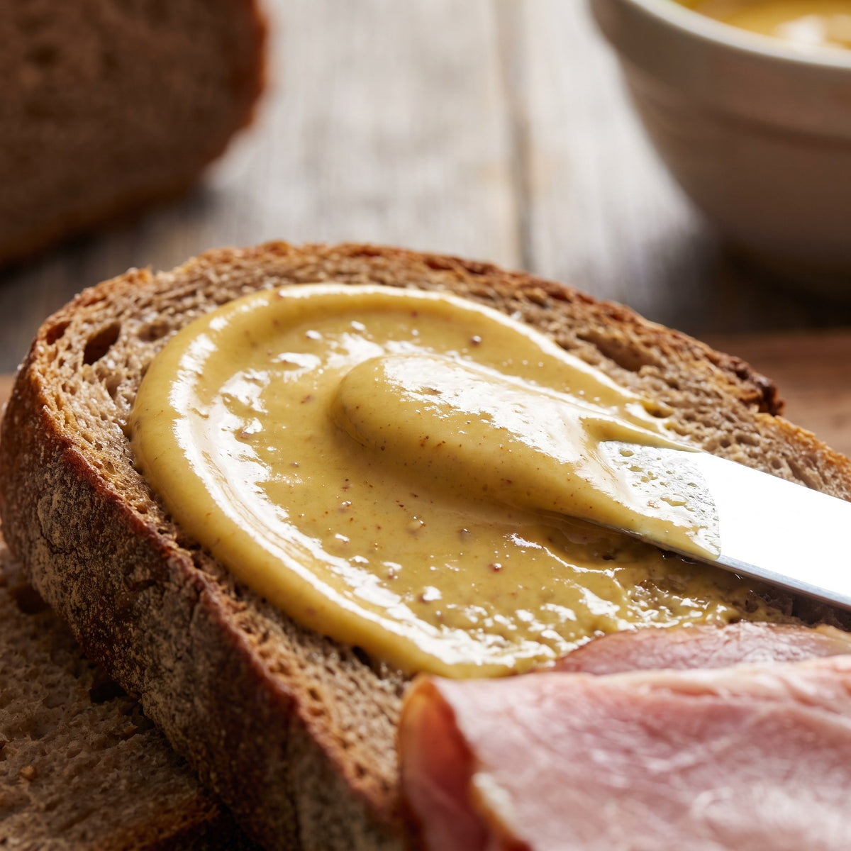 Onctueuse moutarde à l'érable étalée au couteau sur une tranche de pain de campagne avec du jambon