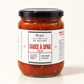 Pot de sauce à spag véggie en verre avec couvercle noir, posé seul sur fond crème