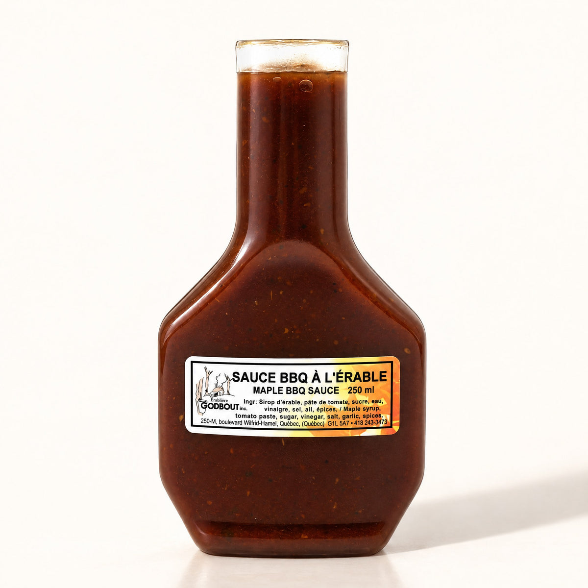 Bouteille de sauce BBQ à l’érable brun foncé, seule sur fond crème, étiquette blanche visible