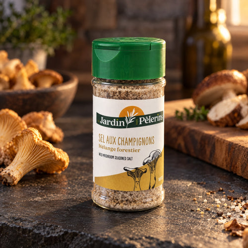 Pot de Sel du Pèlerin aux champignons posé sur une table rustique, avec des chanterelles et du pain en arrière-plan