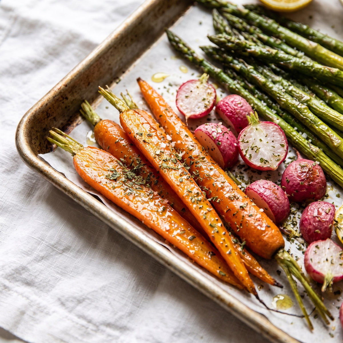 Légumes rôtis sur plaque, dont des carottes et asperges, saupoudrés de Sel du Pèlerin et d’herbes
