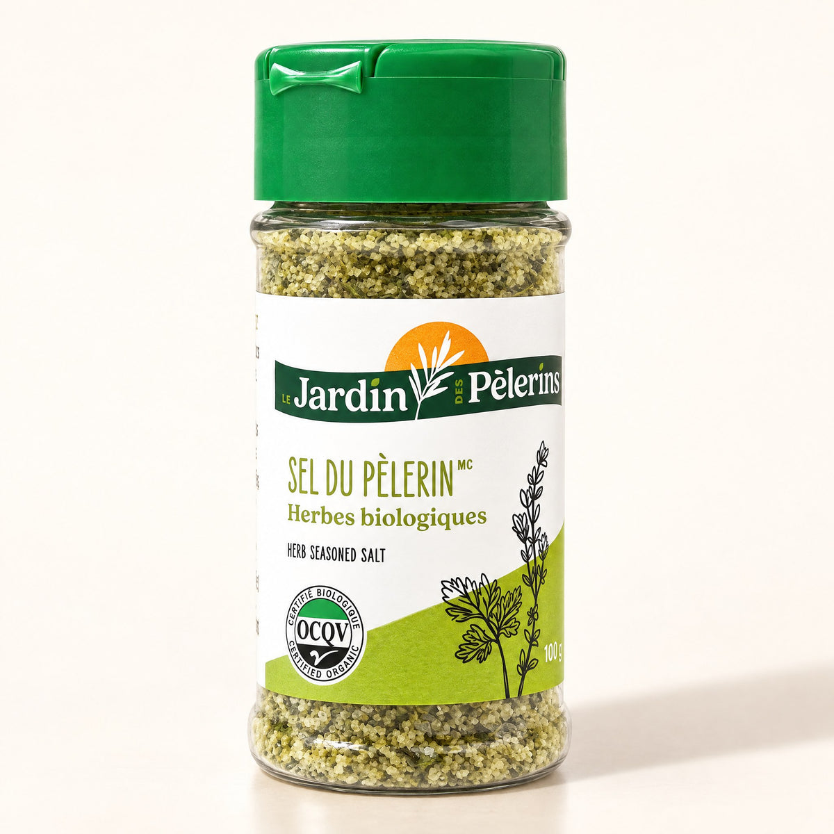 Pot de verre de Sel du Pèlerin, sel aux herbes biologiques avec bouchon vert sur un fond crème