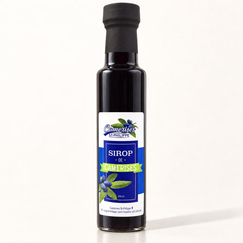 Bouteille de sirop de camerises en verre foncé, étiquette bleue et blanche, sur fond crème