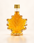 Bouteille de sirop d'érable en forme de feuille, bouchon doré, sur fond crème