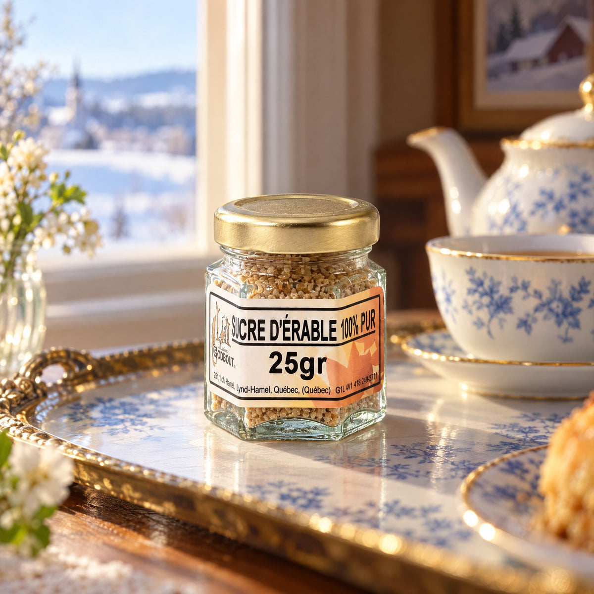 Pot de sucre d’érable 25 g sur un plateau décoratif, devant une fenêtre enneigée avec vaisselle bleue et blanche