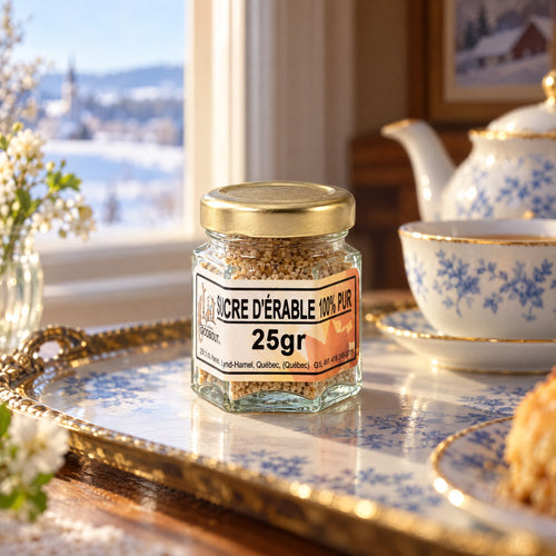 Pot de sucre d’érable 25 g sur un plateau décoratif, devant une fenêtre enneigée avec vaisselle bleue et blanche