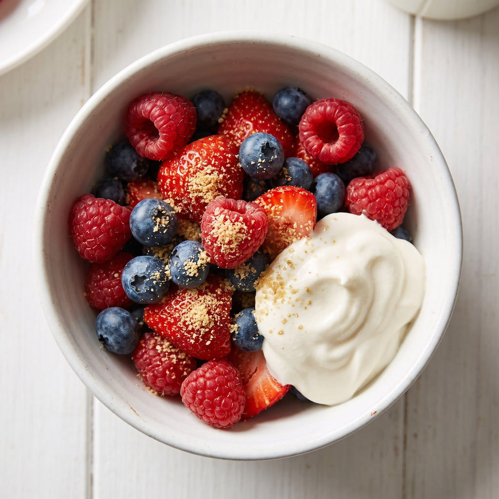 Bol de yogourt garni de petits fruits frais et saupoudré de sucre d’érable, sur table blanche