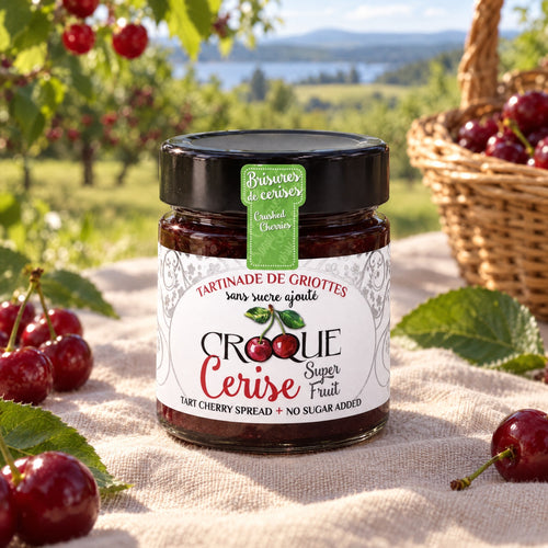 Pot de tartinade de griottes en brisures sur une nappe, avec cerises fraîches, vignes et lac en arrière-plan