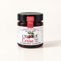 Un pot de verre de tartinade de griottes Croque Cerise avec un couvercle noir, posé sur un fond crème uniforme