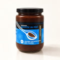 Pot de tartinade ganache au miel au chocolat noir, isolé sur fond crème, couvercle noir