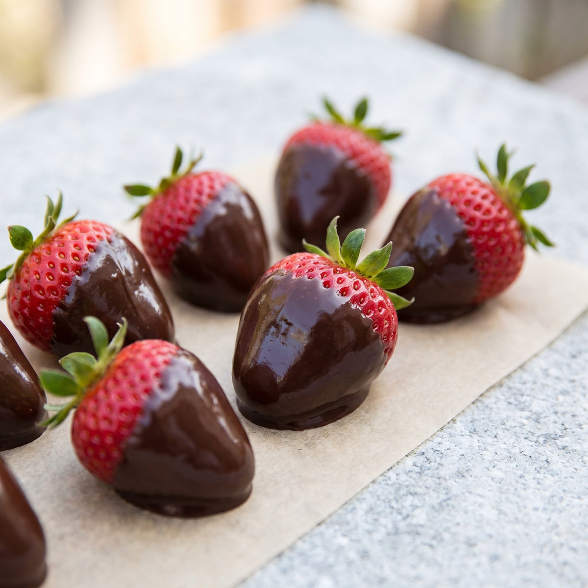 Fraises fraîches trempées dans une ganache au miel brillante, déposées sur papier parchemin