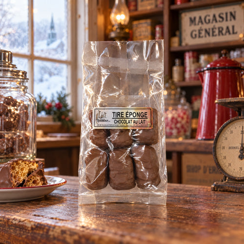 Tire éponge enrobé de chocolat au lait présenté en sachet sur un comptoir de bois dans une épicerie rustique