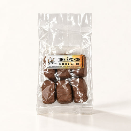Bonbons tire éponge au chocolat au lait, emballés dans un sachet transparent sur fond crème