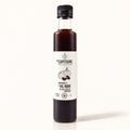 Bouteille de vinaigre à l’ail noir Du Capitaine debout sur fond crème, étiquette blanche visible